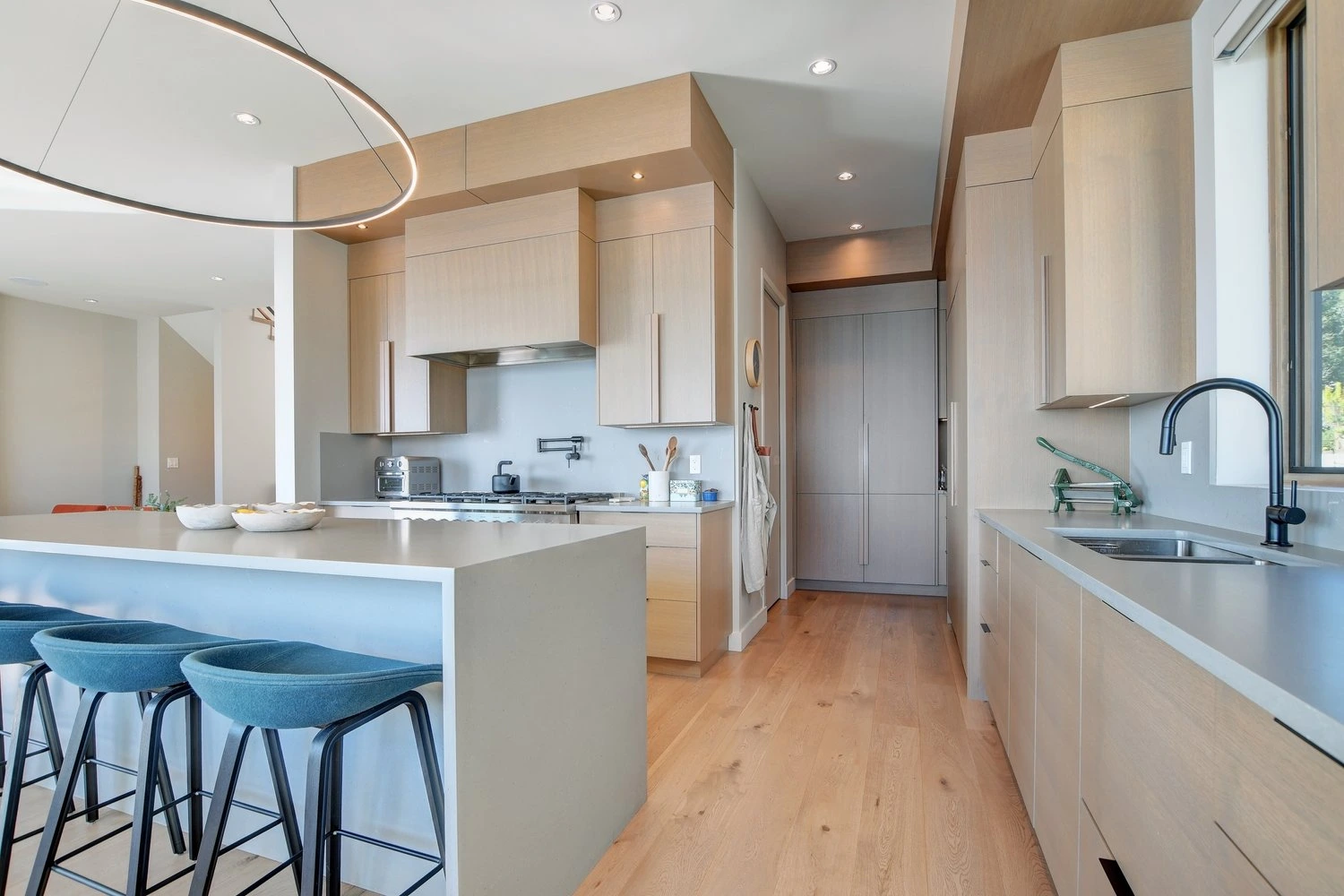Open Concept Kitchen Modern kitchen with light wood cabinetry, curved architectural elements, and waterfront views